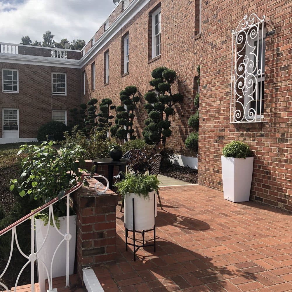 The enclosed brick courtyard with topiary and potted plantings