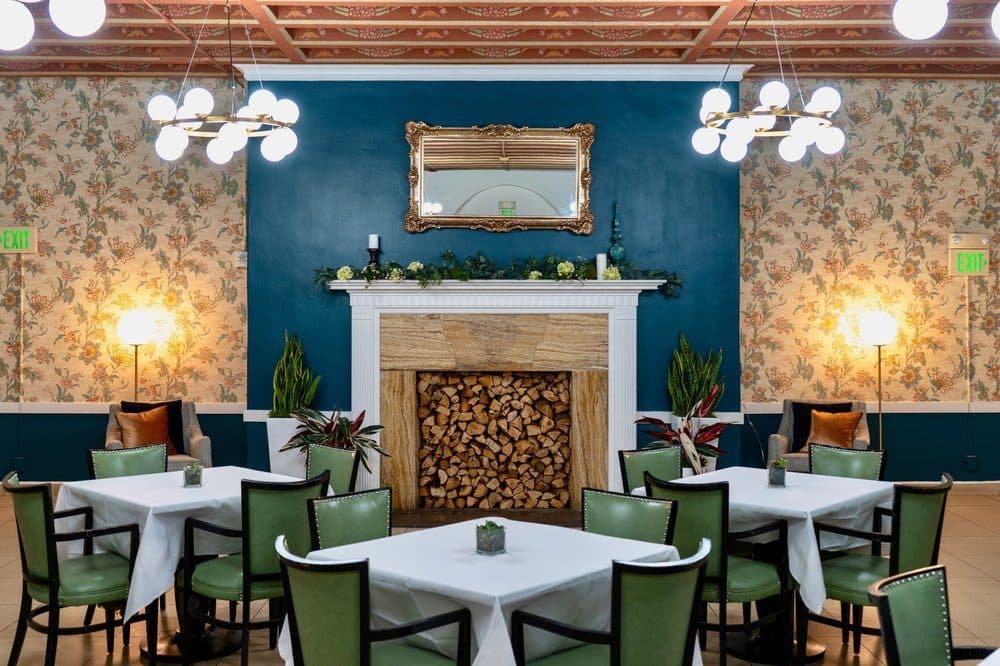 The dining room under the skylight, with set tables and a fireplace