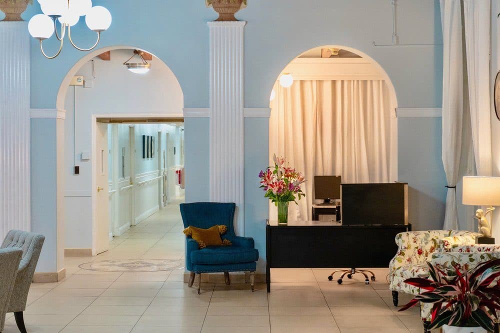 A hallway with an archway and a warm table lamp